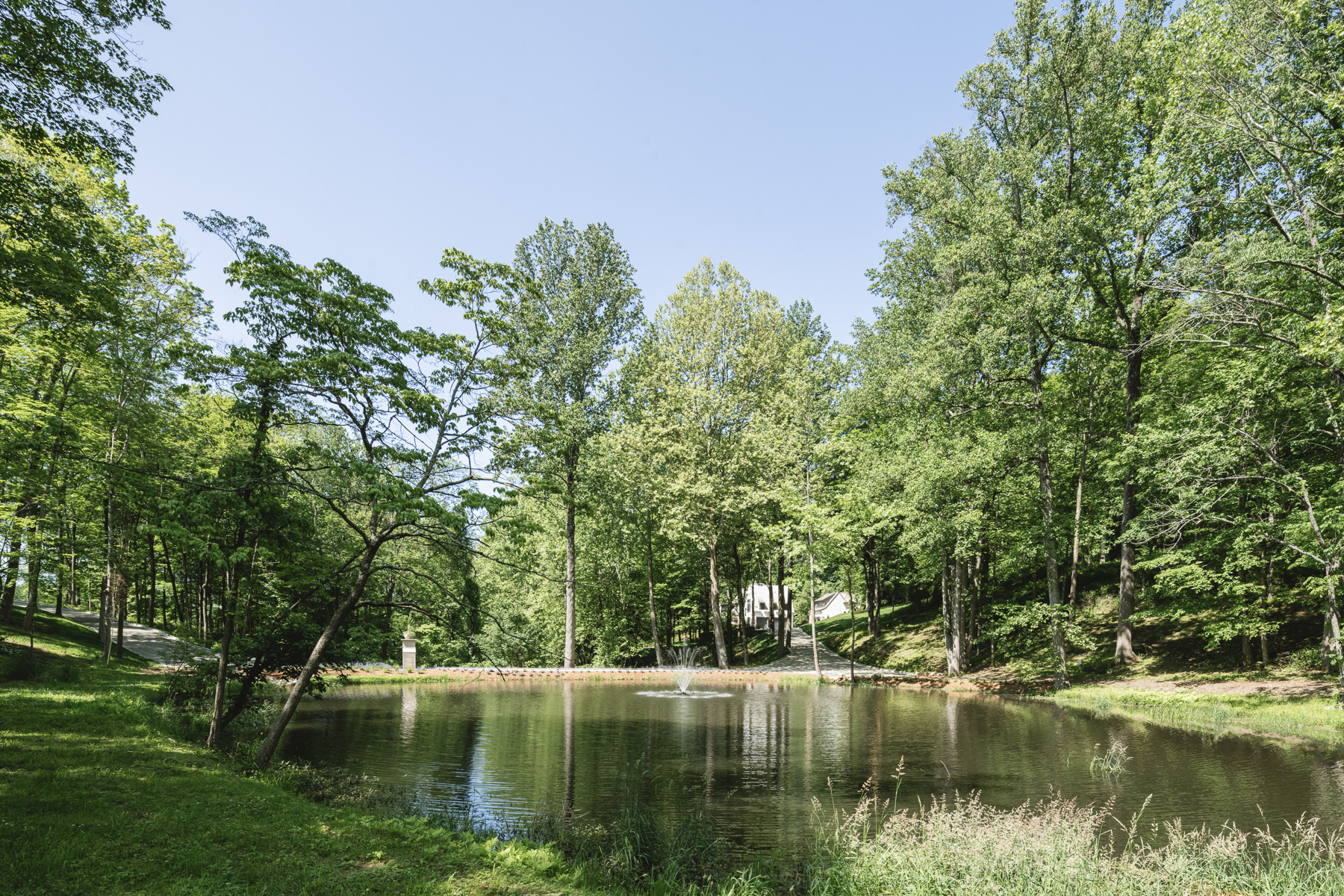 The residence seen across the pond, with trees and planting along the banks